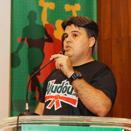 Gestor técnico do Ajudôu durante momento de fala institucional, destacando a importância da liderança, da gestão de pessoas e da organização técnica para a execução qualificada de projetos esportivos sociais. Sua atuação representa a integração entre planejamento, metodologia, acompanhamento de equipes e compromisso com o impacto social por meio do esporte.